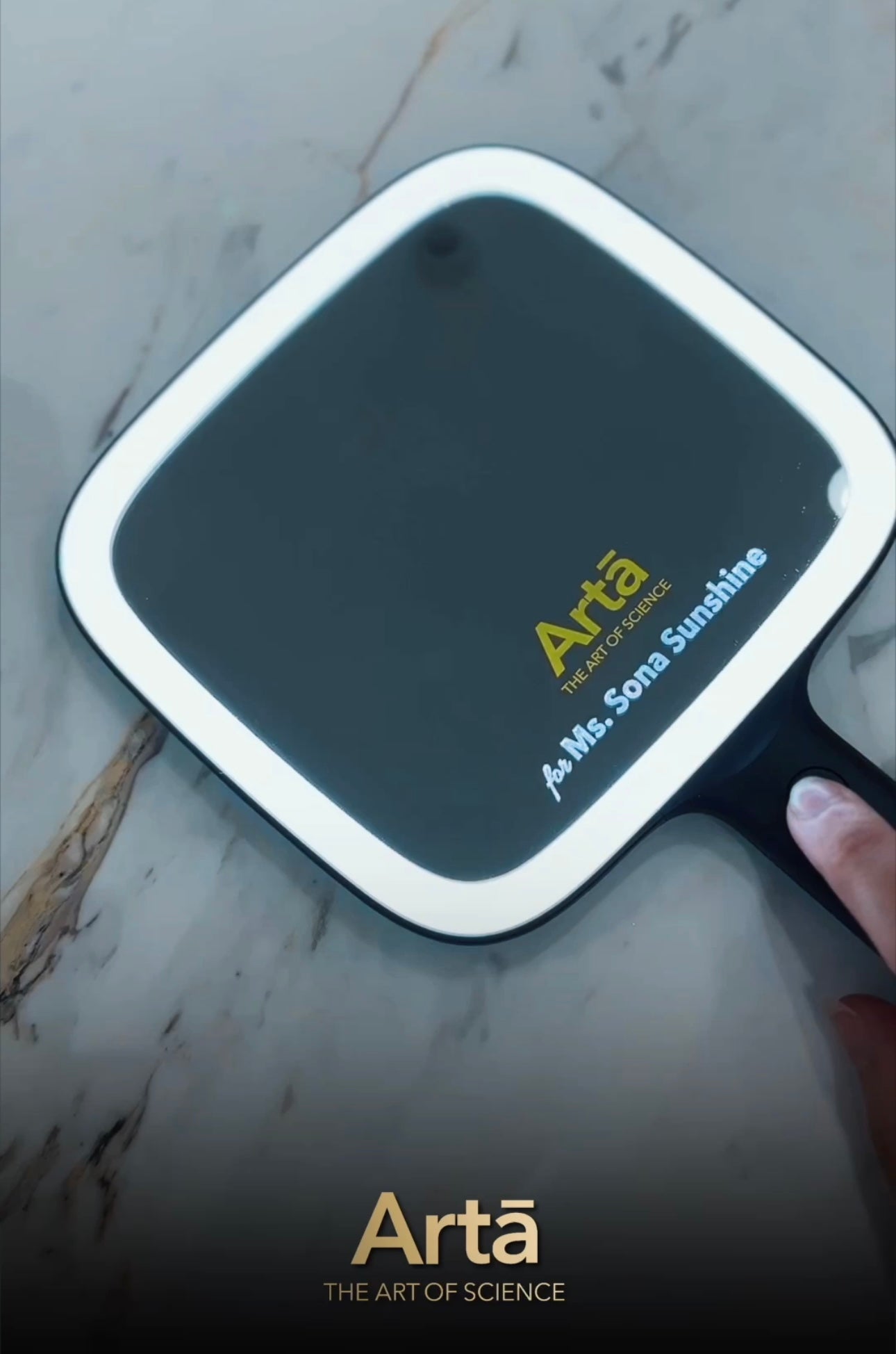 Arta Glow Pro Plus mirror with LED light featuring elegant gold branding “Arta: The Art of Science” and personalized engraving “for Ms. Sona Sunshine.” A luxurious handheld mirror designed for flawless clarity, precision, and beauty.
مرآة آرتا جلو برو بلس بإضاءة LED وشعار ذهبي أنيق “Arta: فن العلم” مع نقش شخصي باسم “لـ Ms. Sona Sunshine”. مرآة فاخرة محمولة تعكس الجمال والدقة بلمسة من الفخامة