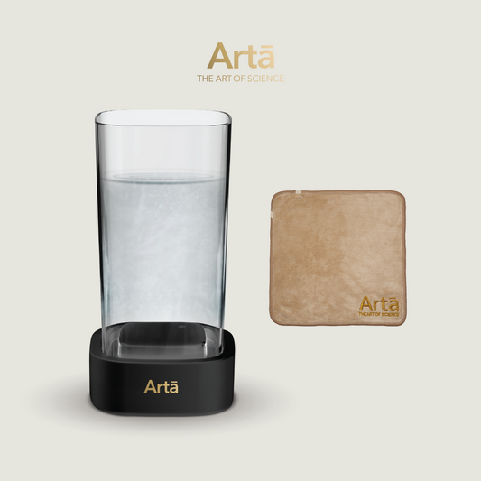 A clear glass with water and a beige card with the brand name 'artĂ' on it, indicating a beauty package.